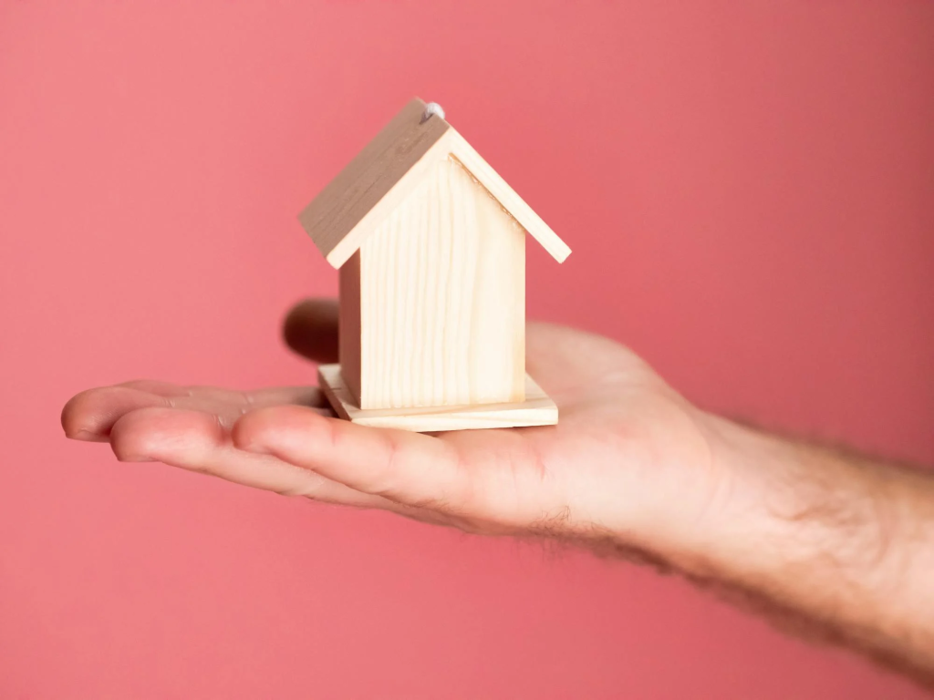 Person Holding Brown Miniature Wooden House